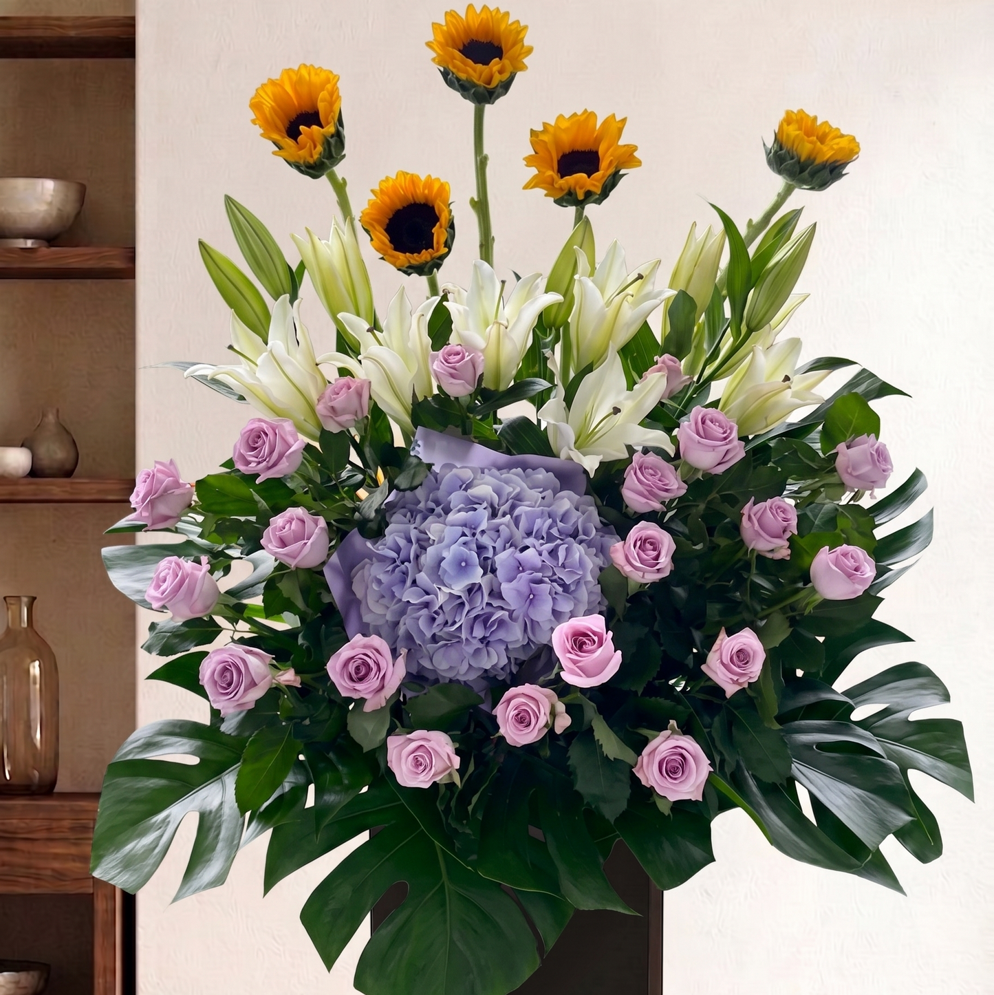 Condolence Floral Stand arrangement with sunflowers, white lilies, and pink roses on a neutral background for next day delivery